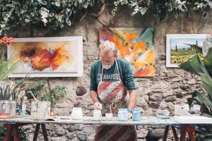 homme peignant sur une table avec des peintures sur le mur en pierre