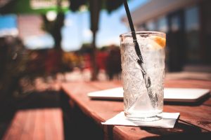 verre avec des glaçons et une paille posé sur une table au soleil