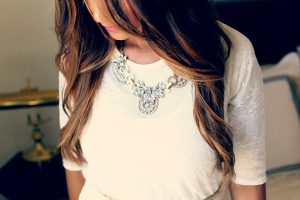 femme brune avec chandail blanc et collier