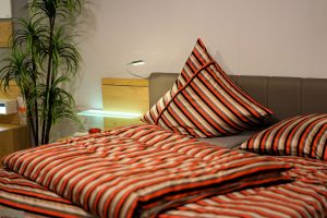 lit d'un hôtel avec des draps rayés orange, noir et blanc