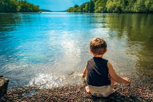 enfant devant un lac dans un parc