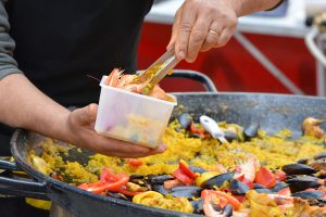 homme servant de la paella dans un récipient