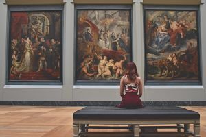 femme assise devant trois peintures