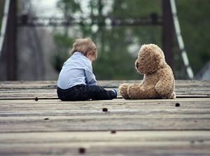 enfant assis devant un ours en peluche