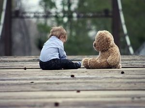 enfant assis devant un ours en peluche