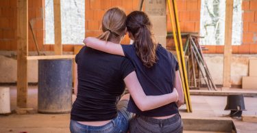 deux filles se prenant dans les bras devant un chantier