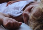 enfant qui dort dans un drap blanc