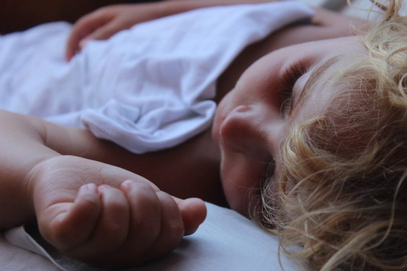 enfant qui dort dans un drap blanc