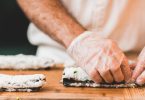 main gantée en train de rouler un sushi