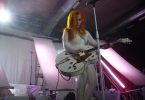 femme rousse en combinaison blanche jouant de la guitare