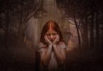 jeune fille rousse se tenant le visage avec les mains autour d'arbres morts
