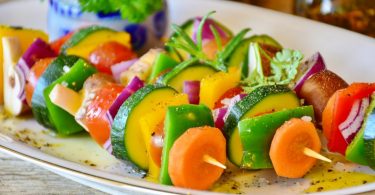 trois brochettes de legumes dans une assiette