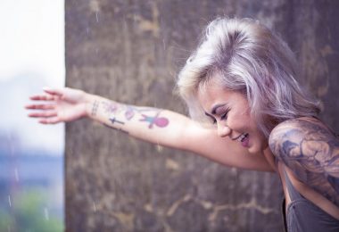 femme souriant avec des tatouages sur le bras