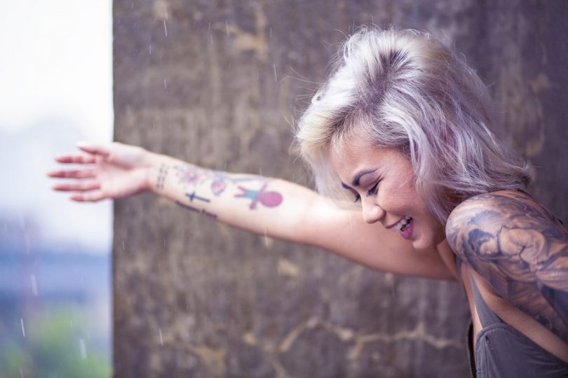 femme souriant avec des tatouages sur le bras