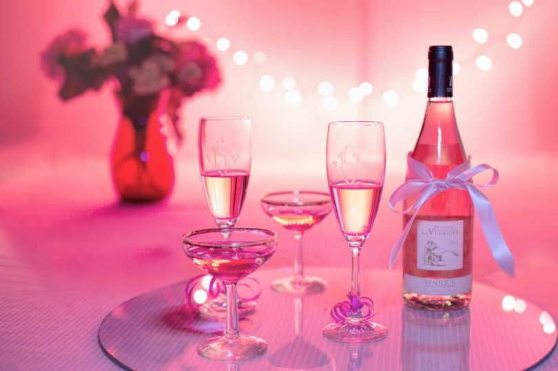 bouteille et duo de coupes de champagne sur fond rose